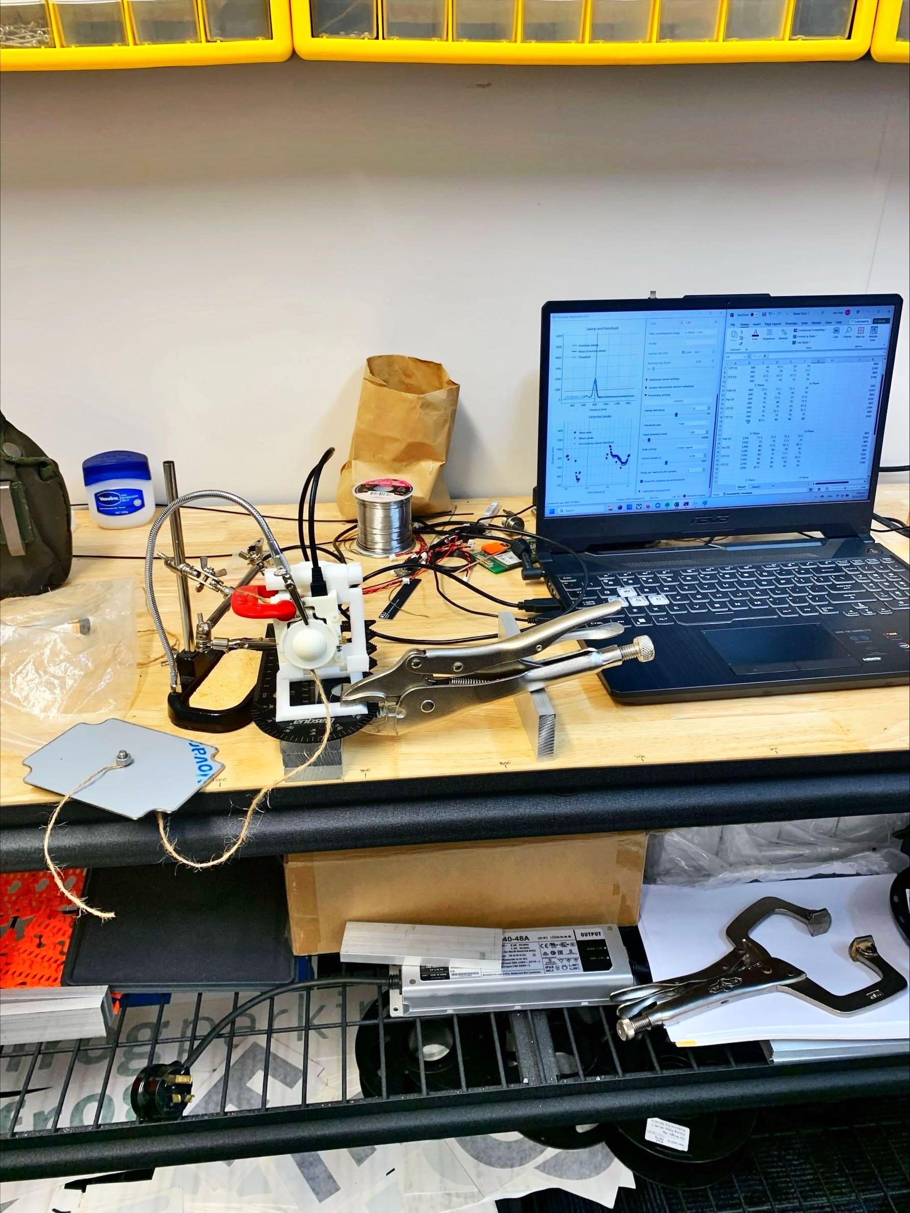 Bench setup with a 3D-printed reflector jig and a laptop showing live radar sweep data